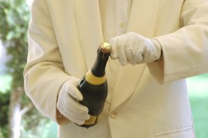 Butler öffnet eine Champagnerflasche